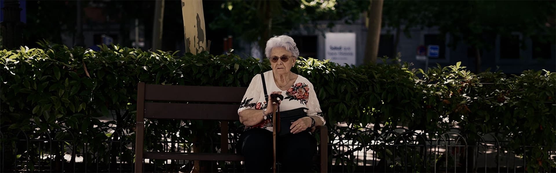Una mujer mayor sentada sola en un banco de un parque