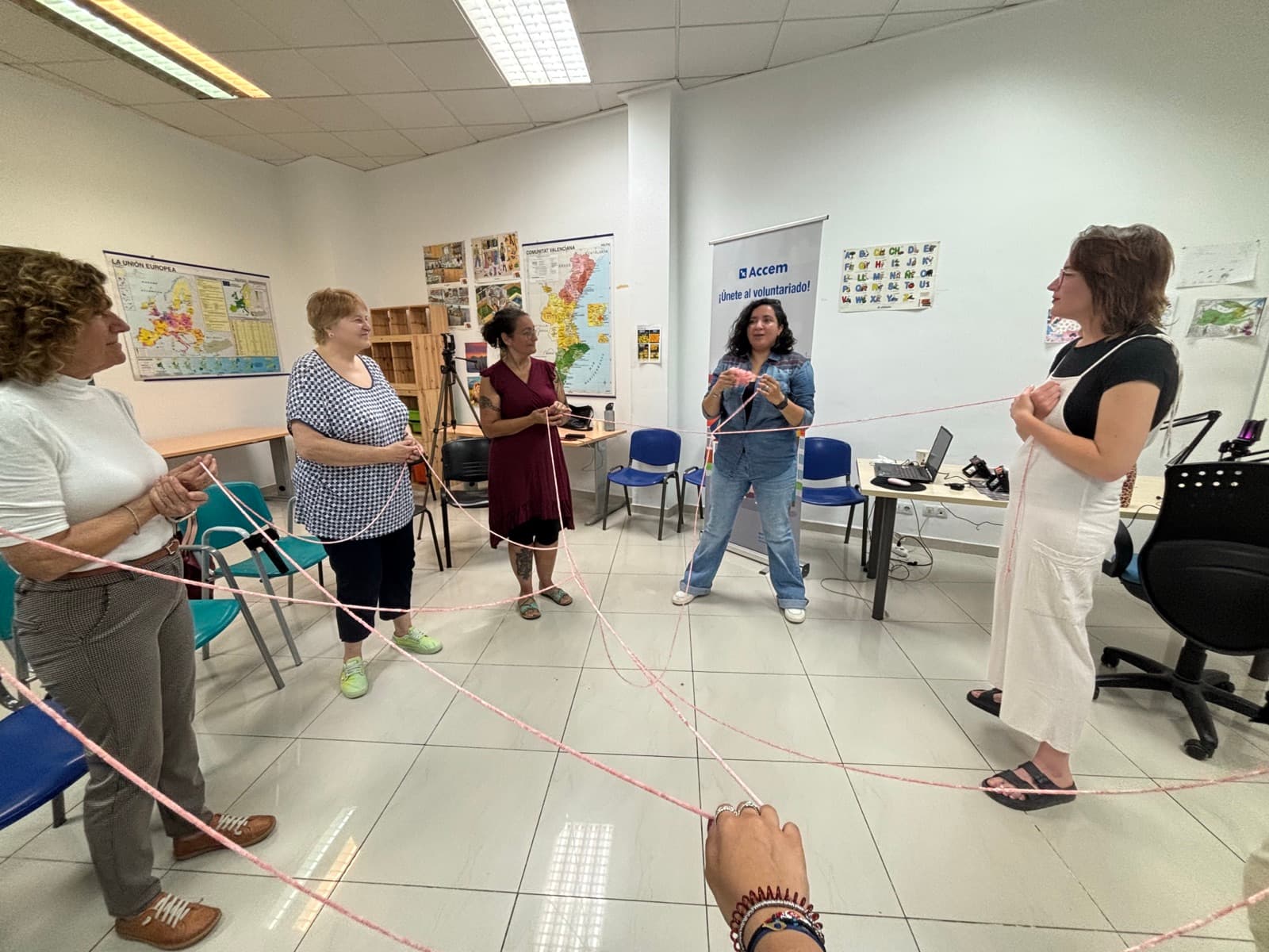 Personas voluntarias de Accem en Valencia sujetan un hilo que las une en una dinámica de grupo
